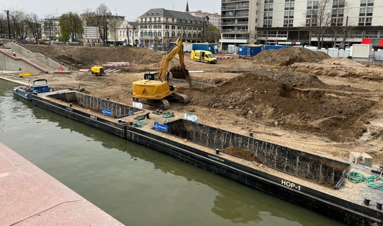 Deux barges de transport fluviales à quai en train d'être chargées de matériaux par une pelleteuse